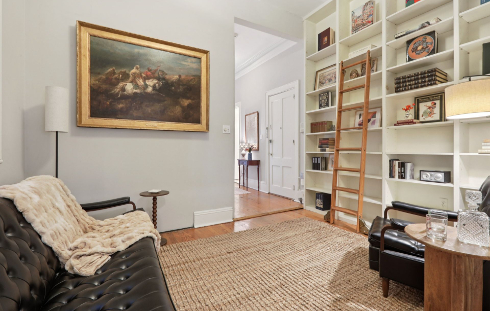 Staged sitting room with leather sofa and floor-to-ceiling bookshelves