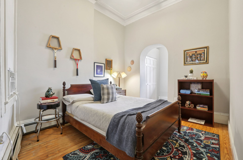Staged bedroom with sleigh bed, vintage tennis rackets, and patterned rug